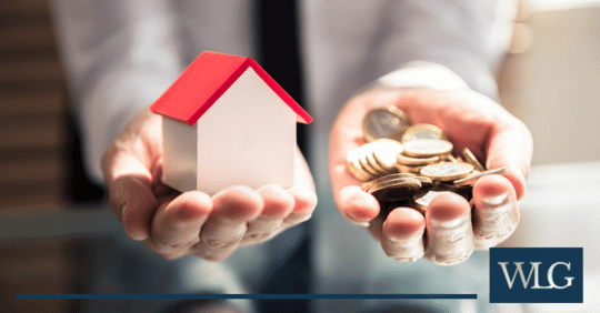 coins and mini home in hands