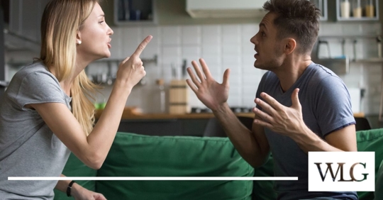 Blonde woman pointing her finger at a man with his hands in the air.