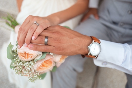 hands of married couple on flower bouquet