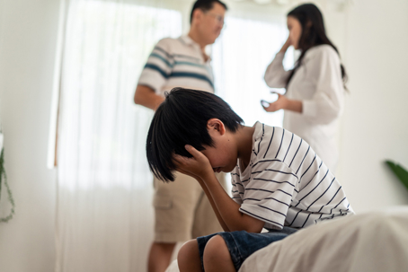 child on bed frustrated with parents fighting
