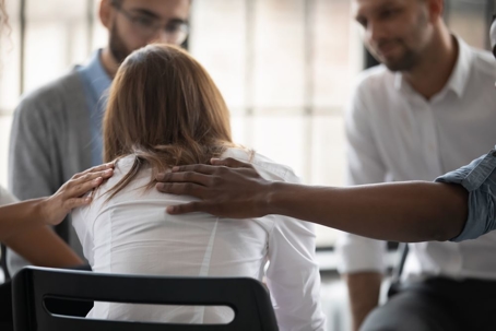 Close up back view unhappy woman with supporting diverse people at therapy session