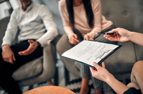 Female lawyer giving documents to husband and wife who are going to divorce.