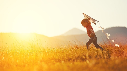 happy child girl with a kite running on meadow in summer in nature