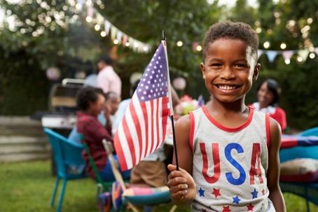 Young boy holding flag at 4th July family garden party